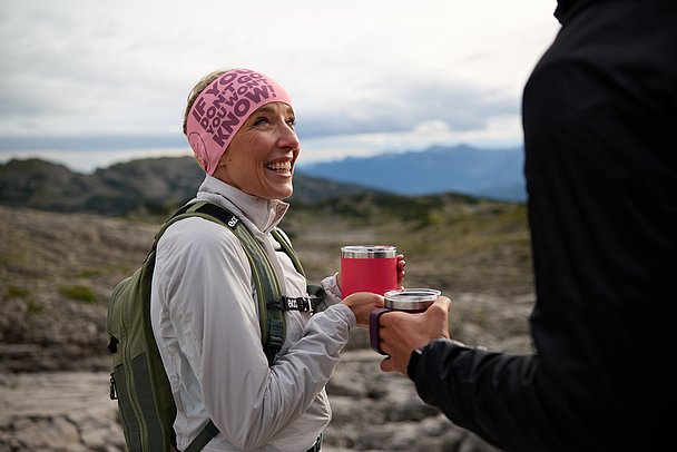 Lachende Frau mit Becher in der Hand auf dem Gottesackerplateau