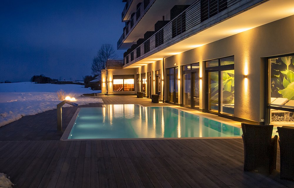 Beleuchteter Pool vor dem Hotel Das Weitblick und verschneiter Landschaft