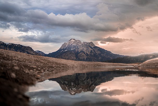 Berg spiegelt sich in einer Pfütze im leeren Forggensee