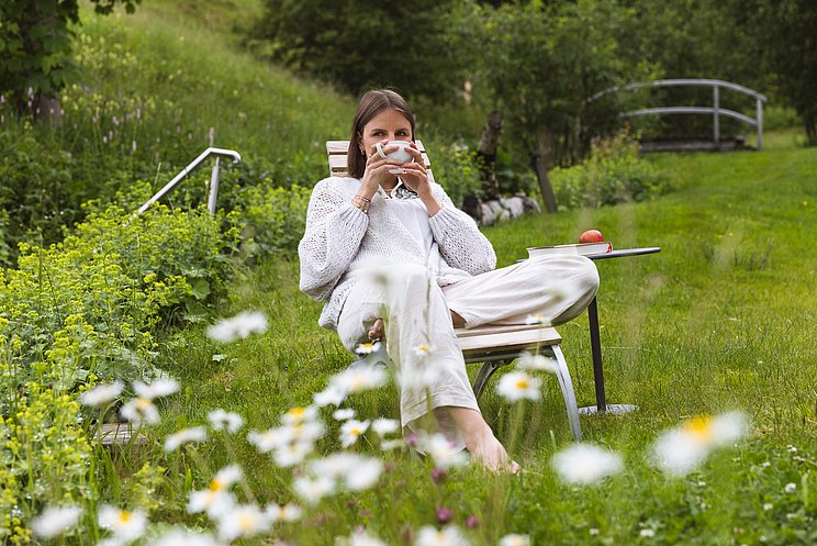 Frau mit Tee sitzt im Garten des Hotels Chesa Valisa Frau mit Tee sitzt im Garten des Hotels Chesa Valisa