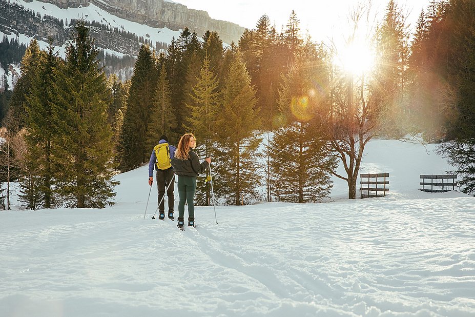 Junge Frau und ein Mann bei Sonnenuntergang, Langlaufen in Rohrmoos
