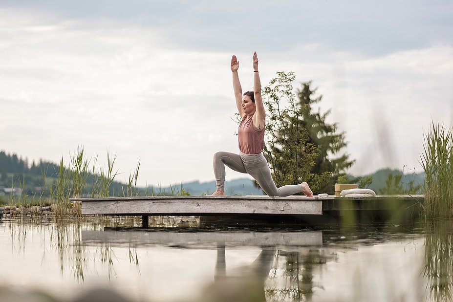Sarina Berchtold macht Yoga auf einer Holzplattform über einem See