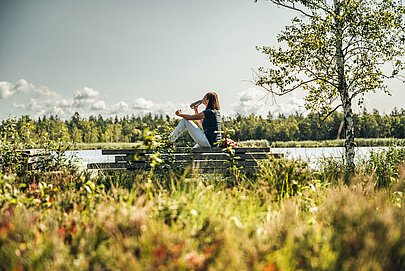 Frau trinkt aus einer Wasserflasche bei einer Pause an einem See