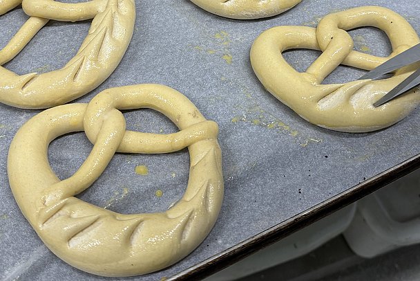 Rohe Palmbrezen auf einem Blech werden mit einer Schere eingeschnitten