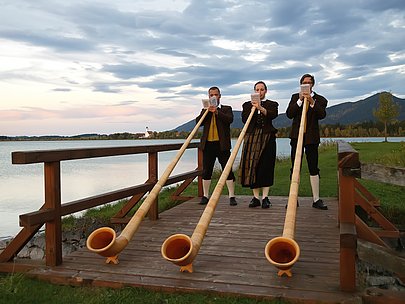 Drei Alphornbläser am Seeufer