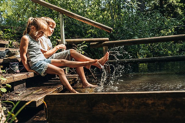 Zwei Kinder spritzen mit dem Füßen in einer Kneipp-Anlage herum