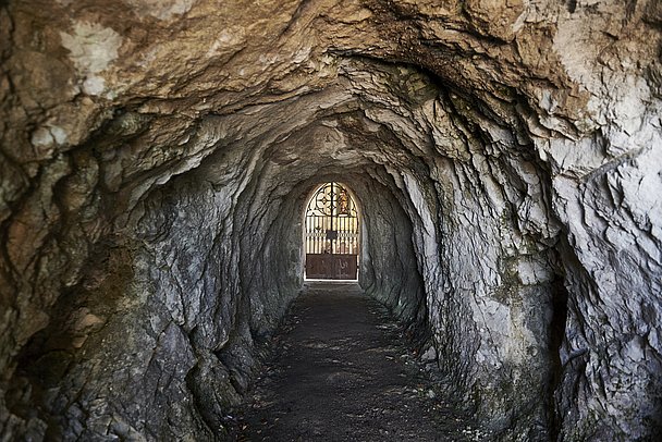 Steinerne Höhle mit einer schmuckvollen Metalltür am Ende