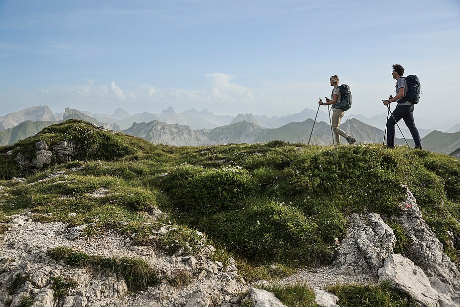 Zwei Wanderer auf einem Bergwanderweg vor Alpenpanorama