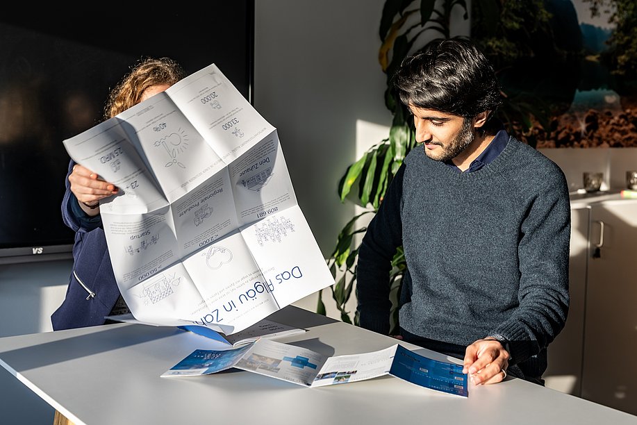 Saqib an einem Tisch mit Faltblättern über das Allgäu Saqib an einem Tisch mit Faltblättern über das Allgäu