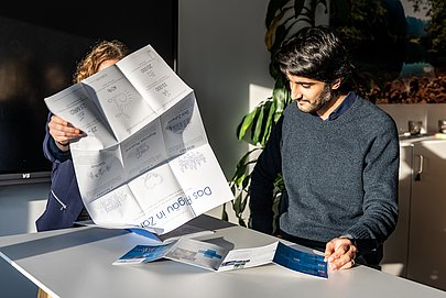Saqib an einem Tisch mit Faltblättern über das Allgäu