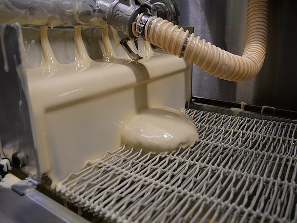 Lebkuchen wird von einer Maschine mit weißen Schokolade überzogen