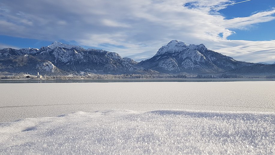 Gefrorener Forggensee und Berge