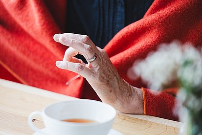 Eine Hand gestikuliert, davor eine Tasse