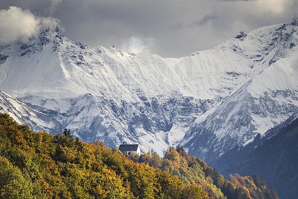Schöllanger Burgkirche auf einem bewaldeten Hügel, im Hintergrund verschneite Berge Schöllanger Burgkirche auf einem bewaldeten Hügel, im Hintergrund verschneite Berge