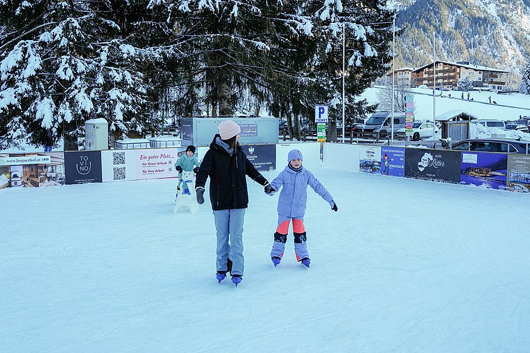 Eine Frau und zwei Kinder auf der Eisbahn im Tannheimer Tal.