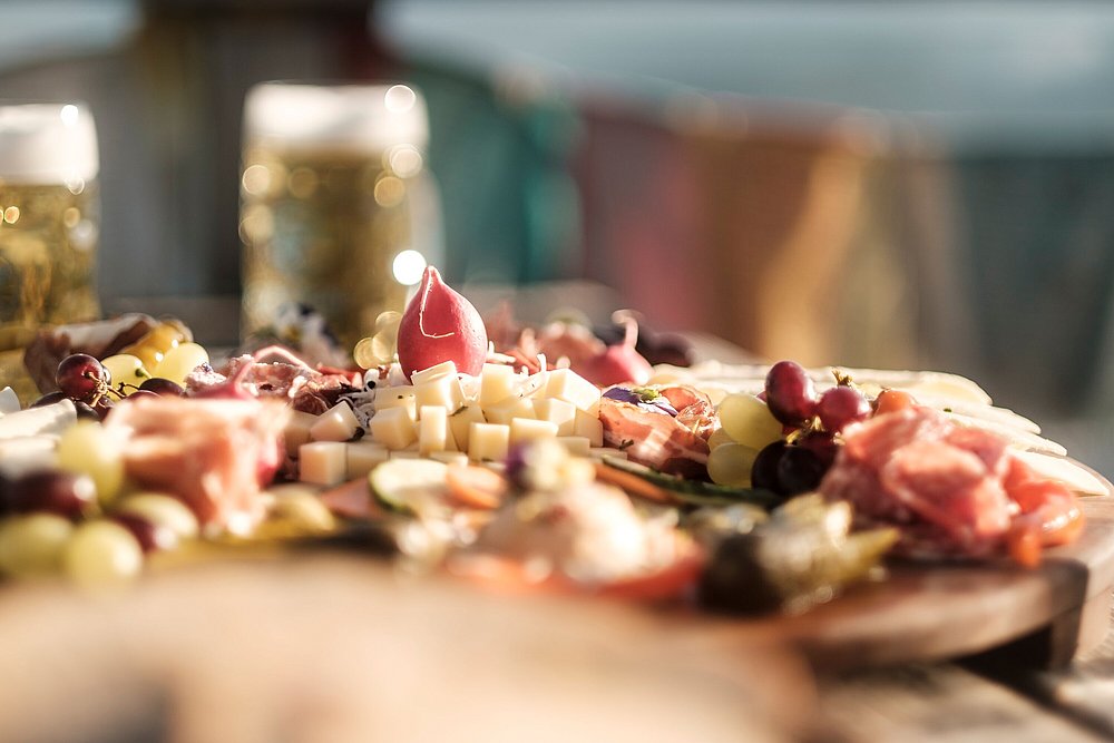 Brotzeit mit Käse und Schinken, im Hintergrund Bier