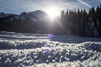 Glitzernder Schnee, während die Sonne hinter den Bergen untergeht Glitzernder Schnee, während die Sonne hinter den Bergen untergeht