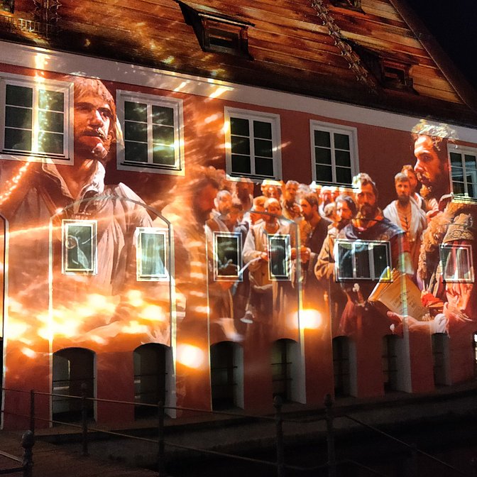 Eine Gruppe von Bauern ist auf eine Hauswand im Memmingen projiziert.