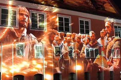 Eine Gruppe von Bauern ist auf eine Hauswand im Memmingen projiziert.