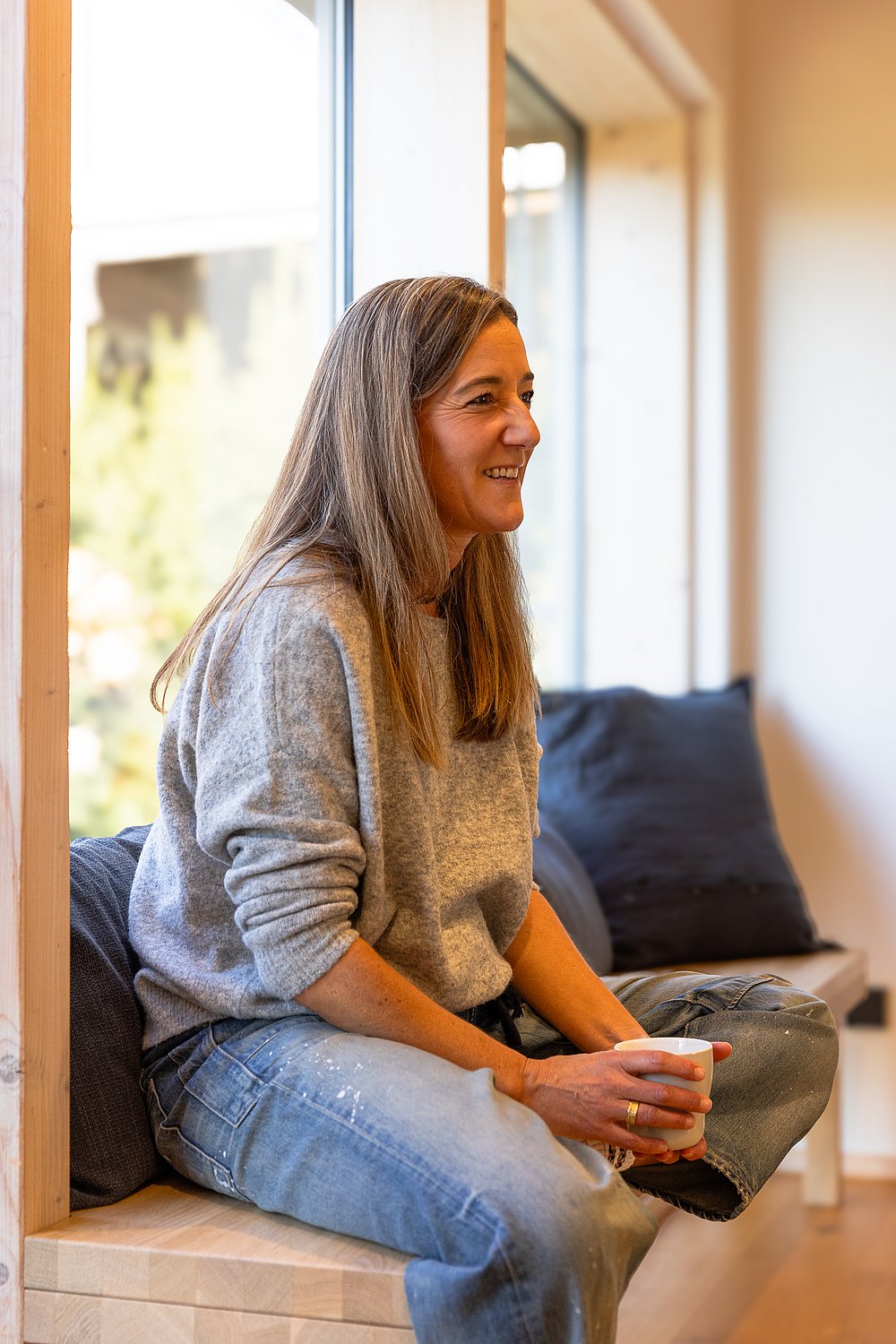 Nina Wolz sitzt auf einer Fensterbank, in der Hand eine Tasse