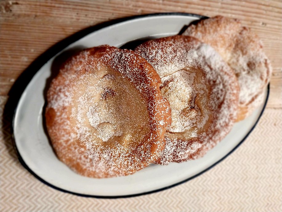 Drei frische Funkenküchle mit Puderzucker