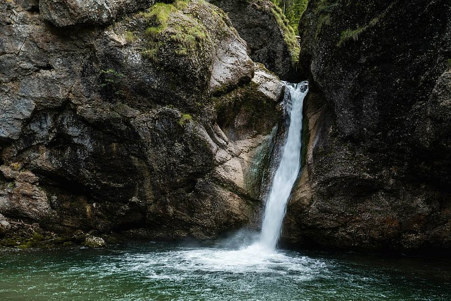 Zwei Frauen sitzen auf den Felsen vor dem Becken an den Buchenegger Wasserfällen