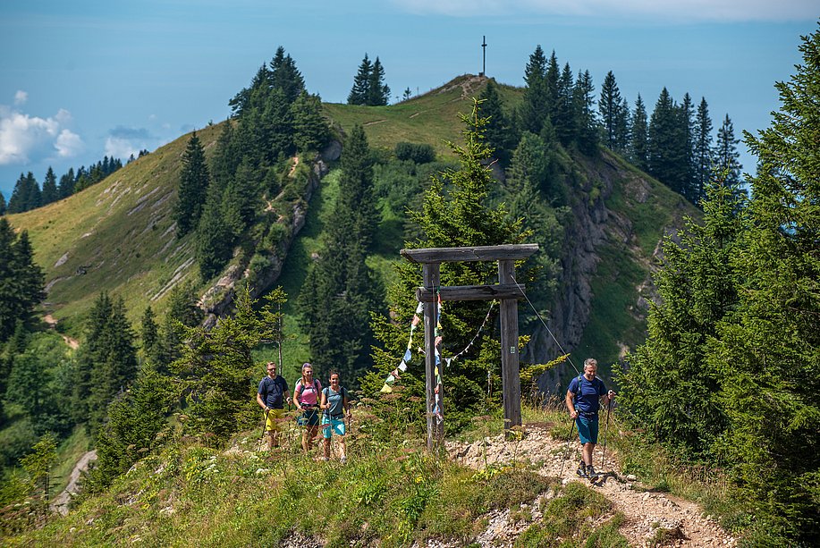 Wanderweg auf einem Berg, Wandergruppe an einem Holztor mit wehenden Gebetsfahnen