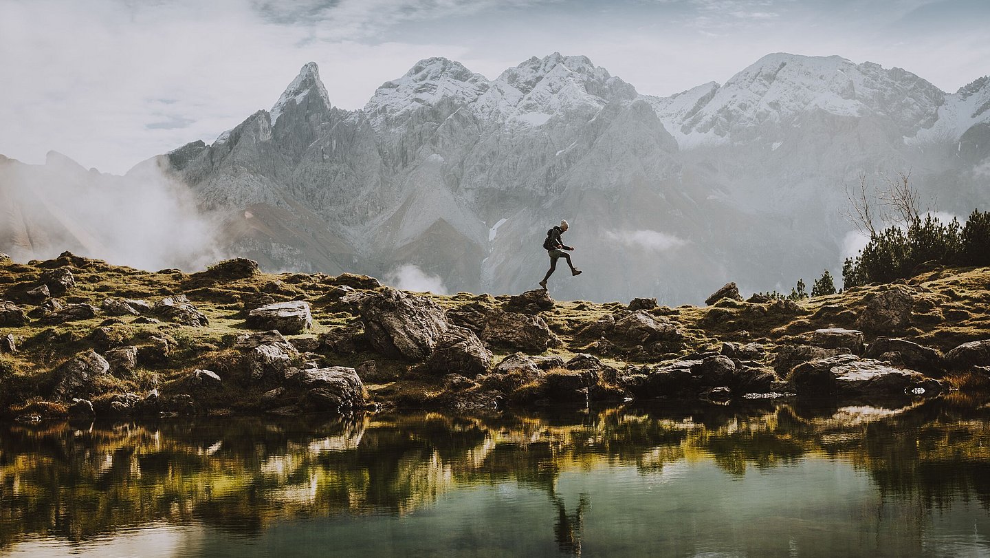 Wanderer an Bergsee mit Bergen im Hintergrund