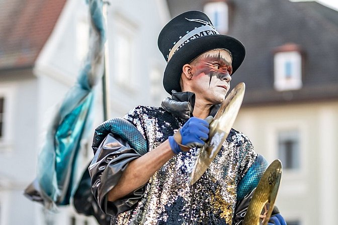 Verkleideter Guggenmusiker spielt Becken in der Memminger Altstadt