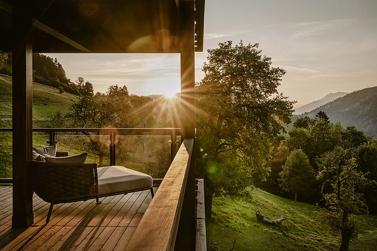 Holzterrasse mit Liegesofa im Morgenlicht