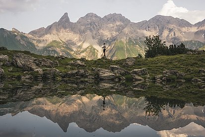 Ein Mann steht vor dem Bergpanorama am Guggersee im Allgäu