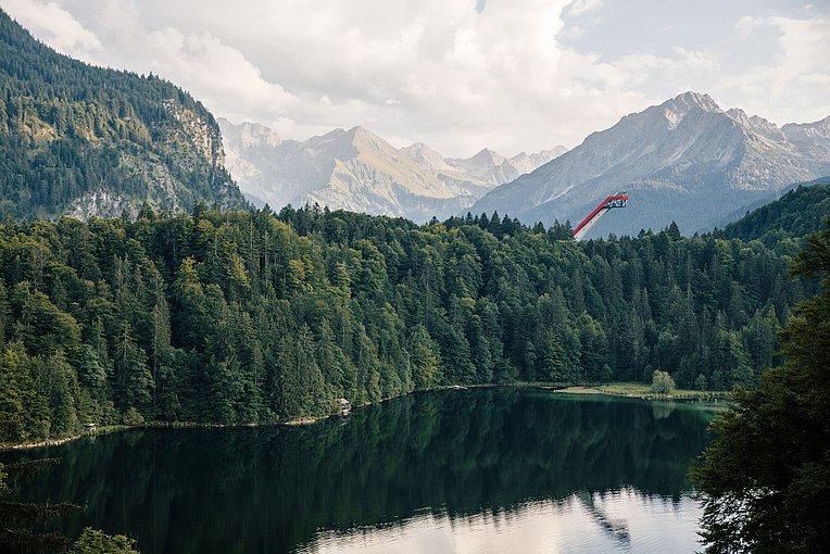 Die Skisprungschanze thront über dem Wald und dem Freibergsee bei Oberstdorf. Im Hintergrund die Allgäuer Alpen Die Skisprungschanze thront über dem Wald und dem Freibergsee bei Oberstdorf. Im Hintergrund die Allgäuer Alpen