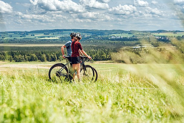 Mann und Frau mit Fahrrad in Voralpenlandschaft im Wurzacher Becken