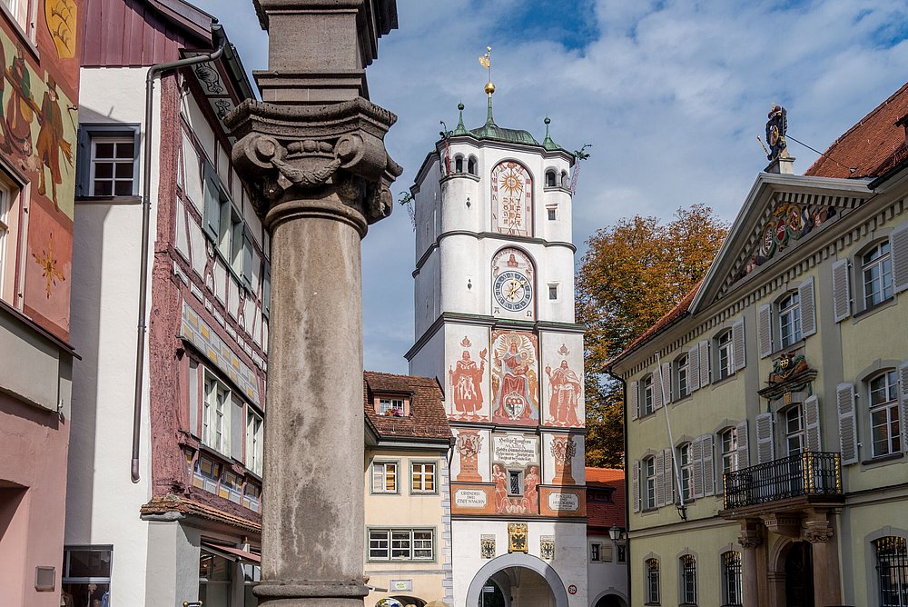 Bemaltes Tor un Wangen, umgeben von historischen Gebäuden, im Vordergrund eine Steinsäule