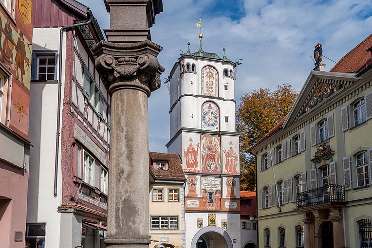 Bemaltes Tor un Wangen, umgeben von historischen Gebäuden, im Vordergrund eine Steinsäule Bemaltes Tor un Wangen, umgeben von historischen Gebäuden, im Vordergrund eine Steinsäule