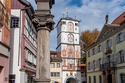 Bemaltes Tor un Wangen, umgeben von historischen Gebäuden, im Vordergrund eine Steinsäule