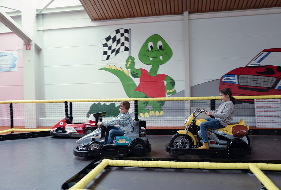 Zwei Kinder fahren auf Bumpercars im Indoorspielplatz