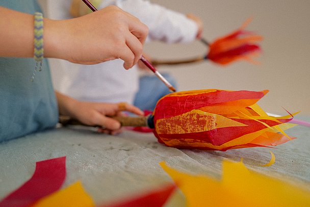 Fackel basteln: Flammen aus Transparentpapier werden auf Flasche geklebt