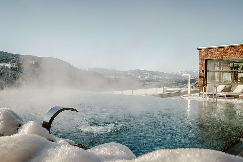 Dampfender Außenpool im Hotel Bergkristall, verschneite Landschaft