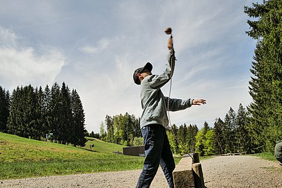 Junge wirft eine Kugel an einer Erlebnisstation am MounTeens-Detektivweg