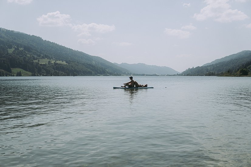 Zwei Personen auf einem SUP auf dem Großen Alpsee mit Bergen am Ufer