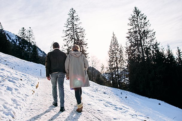 Paar wandert Hand in Hand einen Winterwanderweg entlang Paar wandert Hand in Hand einen Winterwanderweg entlang