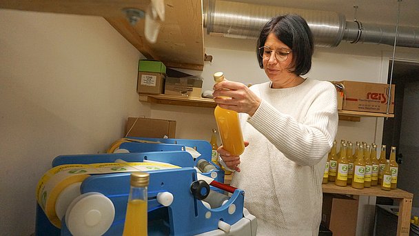 Frau prüft das Etikett auf einer Sirupflasche in der Alpen Zenzero Manufaktur Frau prüft das Etikett auf einer Sirupflasche in der Alpen Zenzero Manufaktur