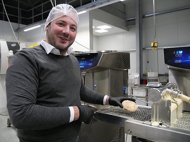 Benjamin Rau legt einen Lebkuchen auf eine Glasiermaschine