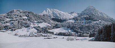 Dorf Rubi vor dem Panorama der weißen Berge, der Himmel ist blau