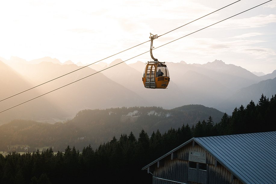 Eine Gondel der Hörnerbahn über der Sennalpe Ornach, im Hintergrund die Berge im Morgenlicht