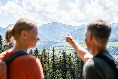 Mann und Frau im Vordergrund, blicken zum Gipfel des Hochgrats im Hintergrund