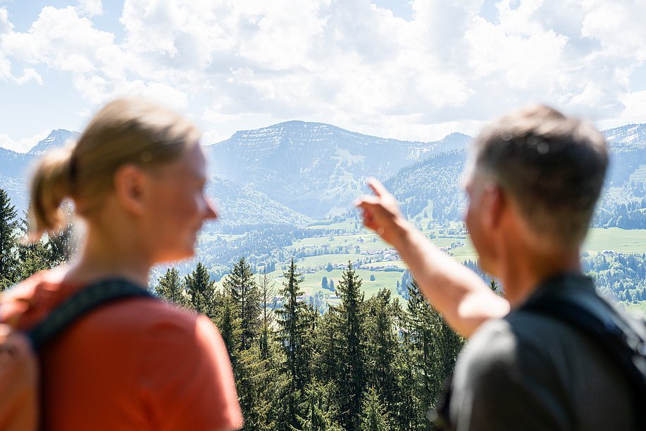 Mann und Frau im Vordergrund, blicken zum Gipfel des Hochgrats im Hintergrund