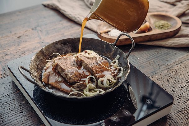 Soße wird zu Zwiebelfleisch in Pfanne gefüllt