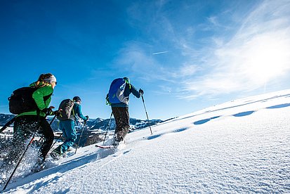 Drei Schneeschuhwanderer mit Blick auf die Nagelfluhkette